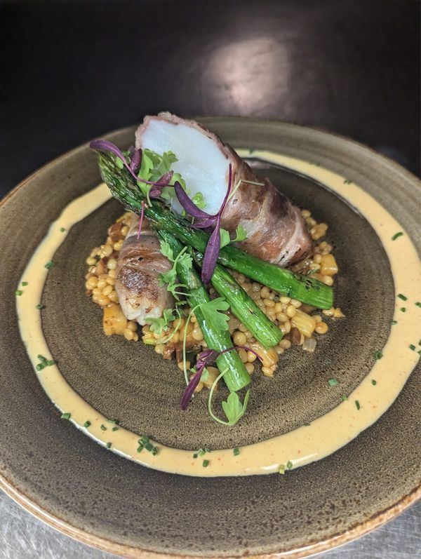 Prosciutto-wrapped fish with asparagus and couscous plated by Chef Brian Schultze, private chef.
